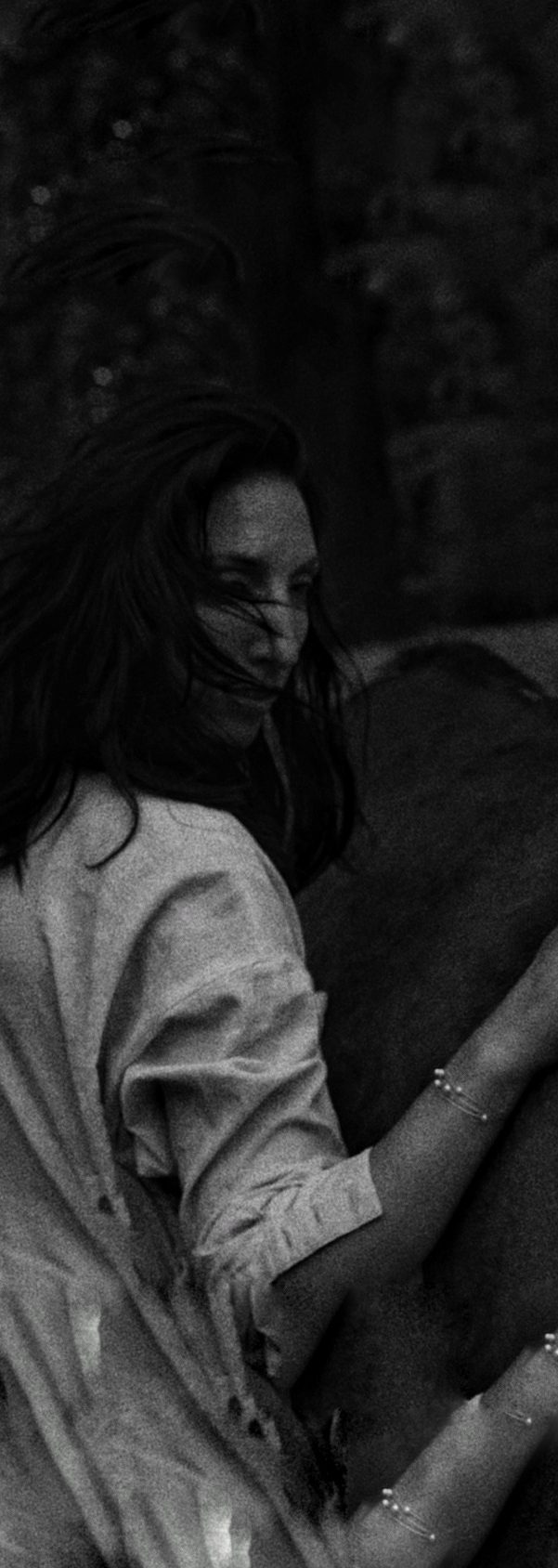Frau berührt Pferd während sie über die Schulter schaut und ihre Haare wild im Gesicht liegen,Raffaela Richter Gohr, Untamed, Ungezähmt, Coaching, Trauma, Breathwork, Sinnlichkeit, Weiblichkeit, Gefühle, Herz Eine Frau schaut über ihre Schulter, umgeben von unscharfen Hintergründen, ihre Hand liegt auf einem Pferd, die Haare wild im Gesicht.