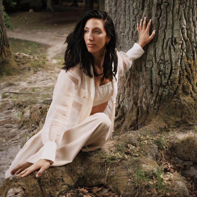 Frau sitzt auf großen Wurzeln an einem Baum im Wald, Verbindung, Selbstfindung, Heilung, Therapie, Coaching, Raffaela Richter, Ungezähmt, Phoenix, Weiblichkeit Frau in heller Kleidung sitzt auf großen Wurzeln an einem Baumstamm in natürlicher Umgebung.